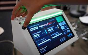 Hospital monitor displaying patient data under a hand poised to press a button