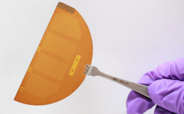 Tweezers holding a thin sheet filled with tiny microgrippers