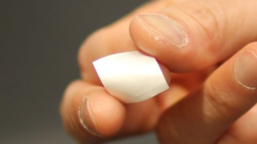 The piezoelectric film, held between thumb and ring finger