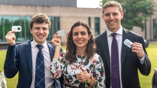 Woman with two younger men holding up a prototype device