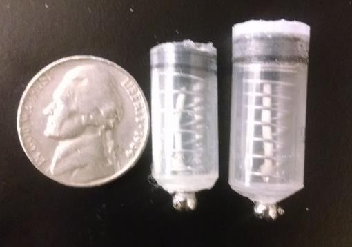 A photo of two versions of the prototype of the smart pill next to a nickel for scale.