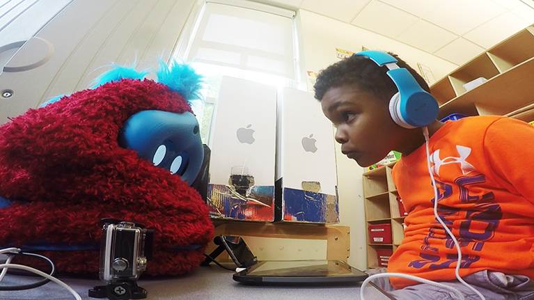 Photo of a preschooler interacting with the social robot companion.