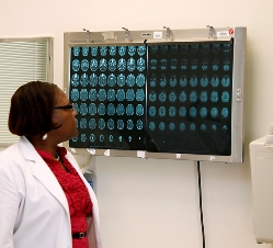 This is a picture of a nurse viewing sequential brain CT scans on an x-ray reader.