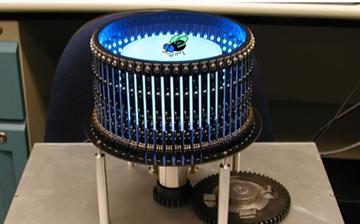 A photo of a circular device with vertical black lines and a blue glow