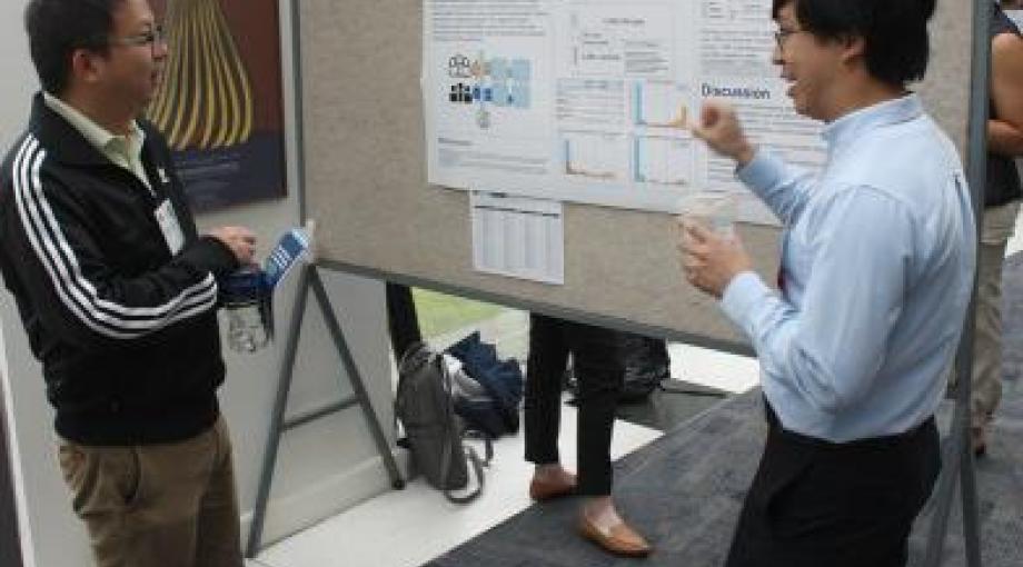 Henry Zheng, at right, presents a poster about his group's research at University of California, Los Angeles, to a fellow trainee