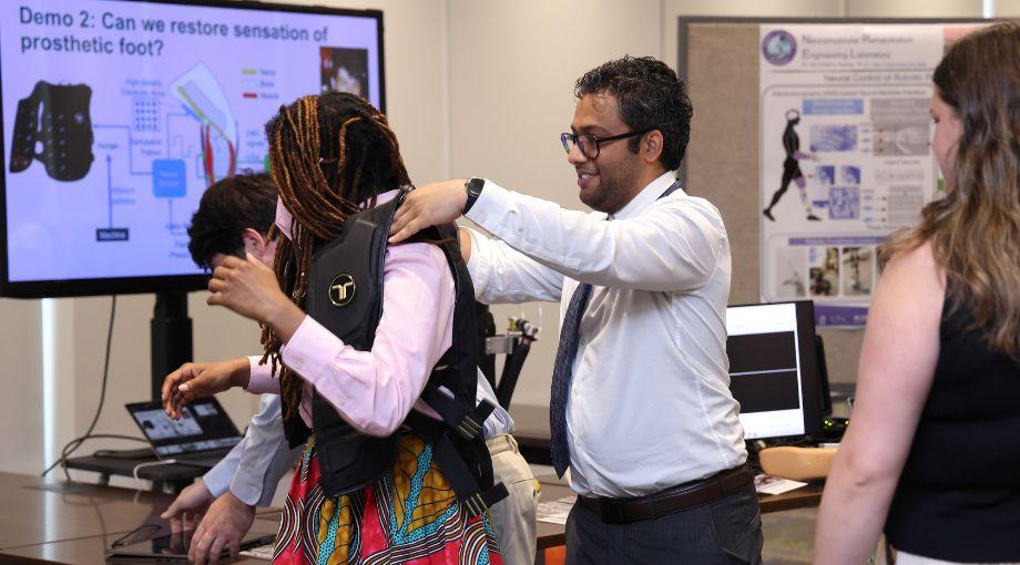 Varun Nalam assists a legislative aide with a vest that provides haptic feedback to the user to improve balance.