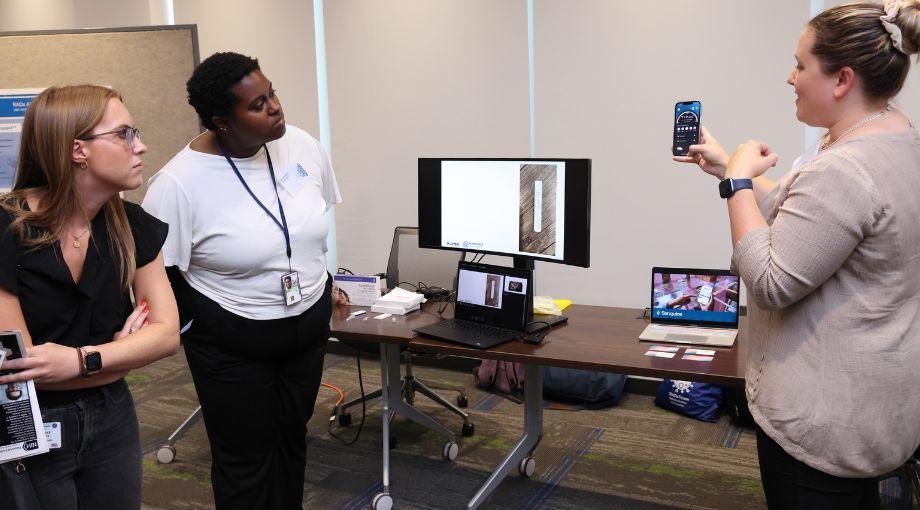 Erika Tyburski (far right), CEO and co-founder at Sanguina, demonstrates how their smartphone app can predict anemia through the estimation of hemoglobin levels by analyzing an image of the fingernail bed.