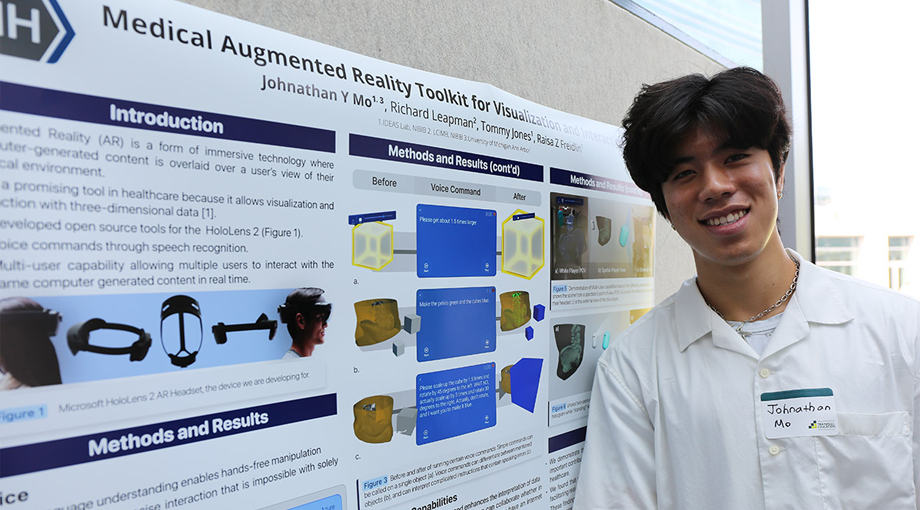 A photo of intern Johnathan Mo posing in front of his scientific poster