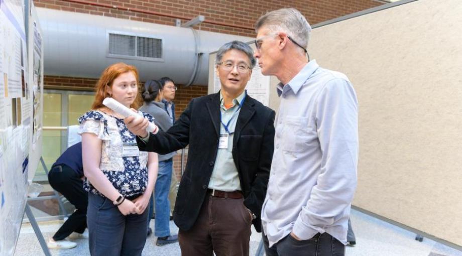 NIBIB Staff Scientist Albert Jin discuss a research poster with conference attendees.